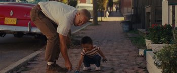 Movie still from “Loving” (2016), directed by Jeff Nichols – A man and a child are playing with a phone; Medium shot, High angle