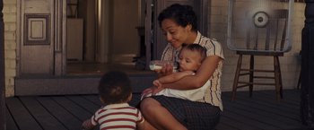 Movie still from “Loving” (2016), directed by Jeff Nichols – A woman holding a baby while sitting next to a boy; Medium shot, High angle