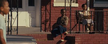 Movie still from “Loving” (2016), directed by Jeff Nichols – A boy sitting on the steps of a brick building; Wide shot, Low angle