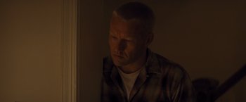 Movie still from “Loving” (2016), directed by Jeff Nichols – A man in a plaid shirt looking out of a window; Close Up shot, High angle
