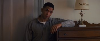 Movie still from “Loving” (2016), directed by Jeff Nichols – A man leaning on a wooden dresser in a room; Close Up shot, Low angle