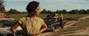 Movie still from “Loving” (2016), directed by Jeff Nichols – A woman standing in front of a parked car; Medium shot, Over the shoulder angle