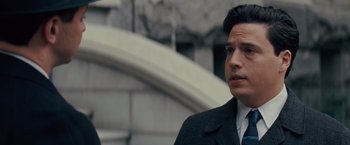 Movie still from “Loving” (2016), directed by Jeff Nichols – A man wearing a suit and tie standing in front of a building; Close Up shot, Over the shoulder angle