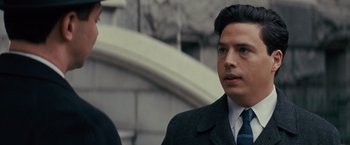 Movie still from “Loving” (2016), directed by Jeff Nichols – A man wearing a suit and tie standing next to a building; Close Up shot, Over the shoulder angle