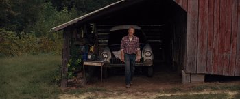 Movie still from “Loving” (2016), directed by Jeff Nichols – A man standing in front of an old car in a garage; Wide shot, Low angle
