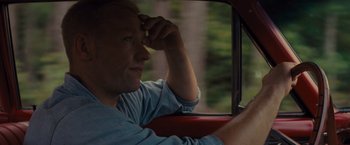 Movie still from “Loving” (2016), directed by Jeff Nichols – A man sitting in the driver's seat of a red car; Close Up shot, Over the shoulder angle