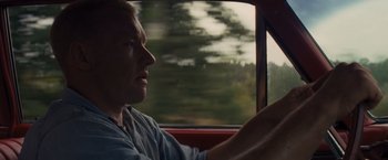 Movie still from “Loving” (2016), directed by Jeff Nichols – A man sitting in the driver's seat of a red car; Close Up shot, High angle