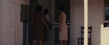 Movie still from “Loving” (2016), directed by Jeff Nichols – A group of women standing next to each other in front of a door; Wide shot, Low angle
