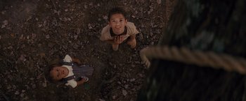 Movie still from “Loving” (2016), directed by Jeff Nichols – A young boy sitting on the ground looking up at the camera; Medium shot, Overhead angle