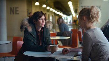 Movie still from “Marcella” (2016), created by Hans Rosenfeldt – A woman sitting at a table with a cup of coffee; Medium shot, Over the shoulder angle