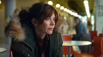 Movie still from “Marcella” (2016), created by Hans Rosenfeldt – A woman sitting at a table in front of lights; Close Up shot, Over the shoulder angle