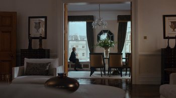 Movie still from “Marcella” (2016), created by Hans Rosenfeldt – A man sitting at a dining room table in front of a window; Wide shot, Over the shoulder angle