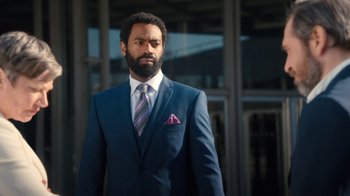 Movie still from “Marcella” (2016), created by Hans Rosenfeldt – A man wearing a suit and tie standing outside; Medium shot, Low angle