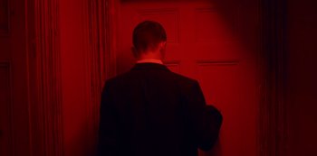 Movie still from “Marcella” (2016), created by Hans Rosenfeldt – A man standing in front of a red door; Medium shot, Low angle