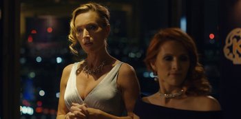 Two women standing next to each other in front of a building at night
