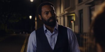 Movie still from “Marcella” (2016), created by Hans Rosenfeldt – A man with a beard wearing a blue shirt and a vest; Close Up shot, Over the shoulder angle