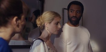 Movie still from “Marcella” (2016), created by Hans Rosenfeldt – A man and a woman standing next to each other in front of a mirror; Medium shot, Over the shoulder angle