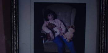 Movie still from “Marcella” (2016), created by Hans Rosenfeldt – A child sitting in a chair holding a teddy bear; Medium shot, High angle