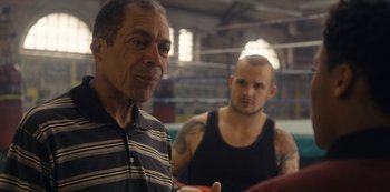 Movie still from “Marcella” (2016), created by Hans Rosenfeldt – Two men in a boxing ring one of which is looking at the camera; Medium shot, Over the shoulder angle