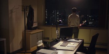 Movie still from “Marcella” (2016), created by Hans Rosenfeldt – A man standing in front of a computer monitor; Wide shot, Over the shoulder angle