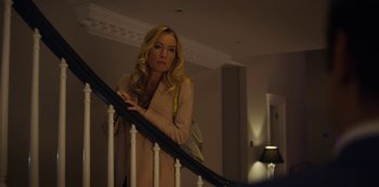 Movie still from “Marcella” (2016), created by Hans Rosenfeldt – A woman standing on top of a white railing next to a staircase; Medium shot, Over the shoulder angle