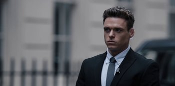 A man wearing a suit and tie standing outside