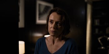 A woman in a blue shirt is looking at the camera
