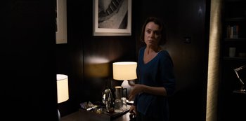 A woman standing next to a table with a lamp on top of it