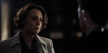 A woman in a white jacket looking at a man in a black suit