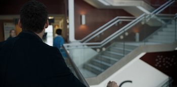A man in a suit sitting in front of a staircase