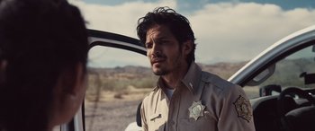 A man in a sheriff's uniform standing next to a car