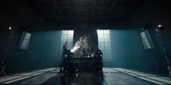 Movie still from “One Piece” (2023), directed by Marc Jobst – A man is sitting in front of a fireplace in a dark room; Wide shot, Low angle