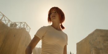 Movie still from “One Piece” (2023), directed by Marc Jobst – A woman with red hair standing in front of some buildings; Medium shot, Low angle