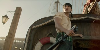 Movie still from “One Piece” (2023), directed by Marc Jobst – A young man holding a gun on top of a boat; Medium shot, Low angle