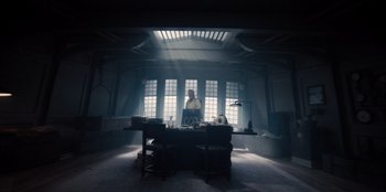 Movie still from “One Piece” (2023), directed by Marc Jobst – A man standing at a desk in a room with windows; Wide shot, Low angle