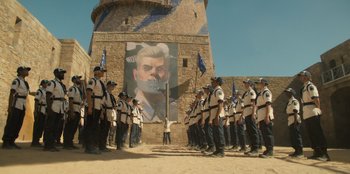 Movie still from “One Piece” (2023), directed by Marc Jobst – A group of men standing next to each other in front of a building; Extreme Wide shot, Low angle