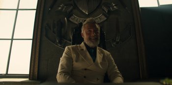 Movie still from “One Piece” (2023), directed by Marc Jobst – An older man wearing a suit and smiling; Medium shot, Low angle
