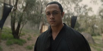 Movie still from “One Piece” (2023), directed by Marc Jobst – A man with long black hair wearing a black shirt; Close Up shot, Over the shoulder angle