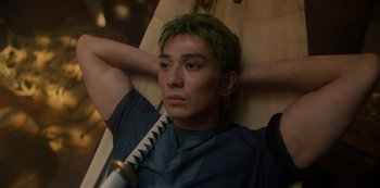 Movie still from “One Piece” (2023), directed by Marc Jobst – A man with green hair holding a baseball bat; Medium shot, High angle