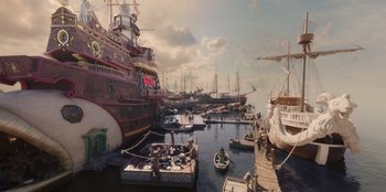Movie still from “One Piece” (2023), directed by Marc Jobst – A group of boats docked in a harbor; Extreme Wide shot, High angle