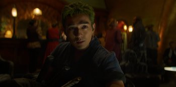 Movie still from “One Piece” (2023), directed by Marc Jobst – A man with green hair is posing for a picture; Close Up shot, Over the shoulder angle