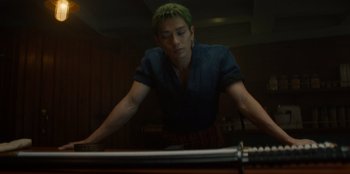 Movie still from “One Piece” (2023), directed by Marc Jobst – A man with green hair is playing a game of billiards; Medium shot, Low angle
