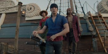 Movie still from “One Piece” (2023), directed by Marc Jobst – A group of men standing on top of a boat; Medium shot, Low angle