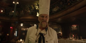 Movie still from “One Piece” (2023), directed by Marc Jobst – A man in a chef's outfit with a beard; Medium shot, Low angle