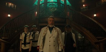 Movie still from “One Piece” (2023), directed by Marc Jobst – A group of men standing next to each other in front of a building; Wide shot, Low angle