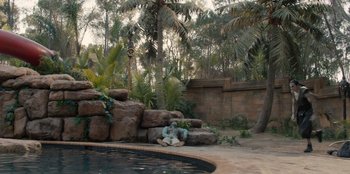 Movie still from “One Piece” (2023), directed by Marc Jobst – A man sitting on the ground next to a swimming pool; Extreme Wide shot, High angle
