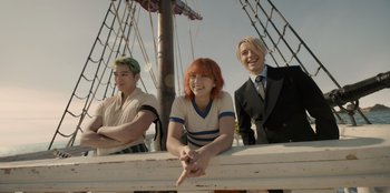 Movie still from “One Piece” (2023), directed by Marc Jobst – A group of people sitting next to each other on top of a boat; Medium shot, Low angle