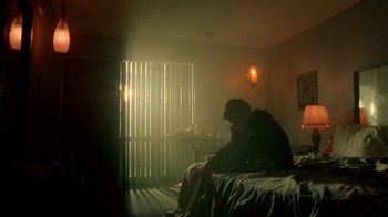 Movie still from “Breaking Bad” (2008), created by Vince Gilligan – A person sitting on a bed in a room; Wide shot, Low angle
