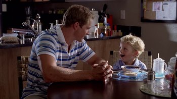 Movie still from “Breaking Bad” (2008), created by Vince Gilligan – A man and a boy sitting at a dining table; Medium shot, Over the shoulder angle