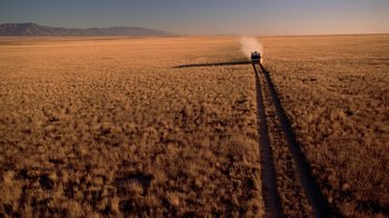 Movie still from “Breaking Bad” (2008), created by Vince Gilligan – A car driving down a dirt road through a field; Extreme Wide shot, High angle
